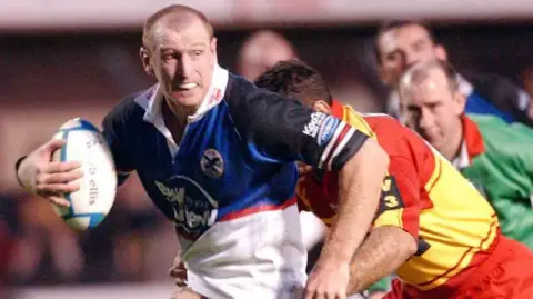 Warriors' Gareth Thomas is caught by Ludovic Loustau of Perpignan
