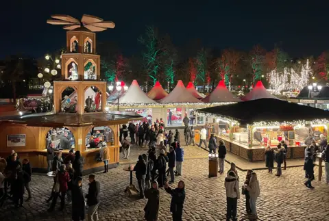 High angle photos of Berlin Christmas market. People stand at wooden stalls