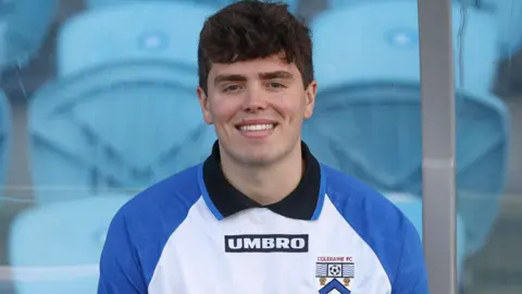 Pacemaker Henry Ross has thick black hair and is smiling. He is wearing a Coleraine FC football top