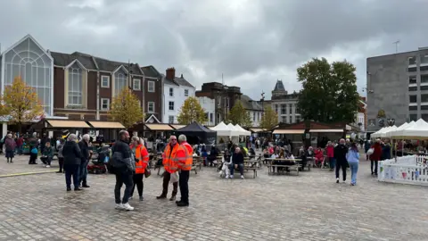 Northampton Market Square. A large number of people are gathered in social groups on the newly opened Market Square. 