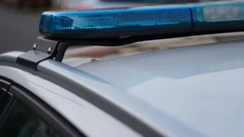 Close-up shot of a police car's blue lights, which are not lit. The roof of the car is white.