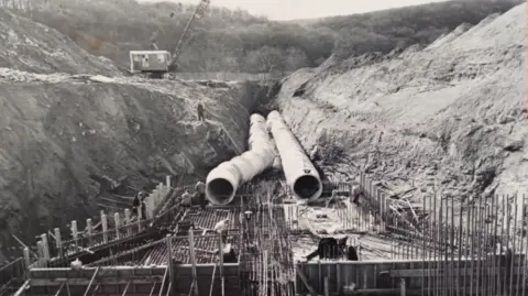 Severn Trent A black and white image showing construction under way of Trimpley Reservoir, showing the major pipes that sit beneath the surface, after huge excavations of earth have taken place