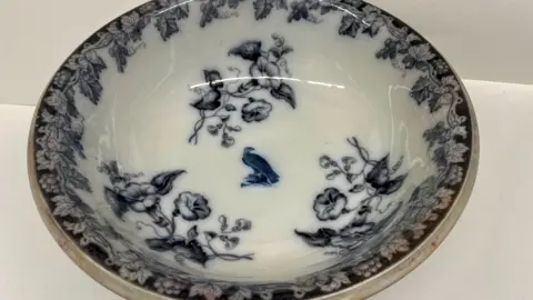 A professional image of a white serving bowl with an intricate dark blue floral and bird pattern