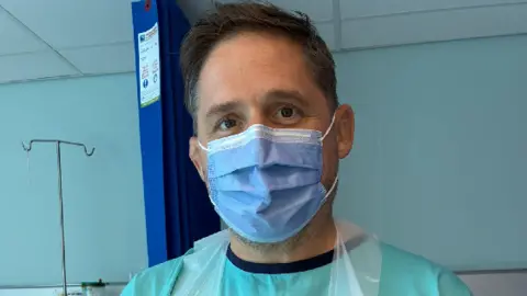 Rhys Thomas wearing a medical mask and apron