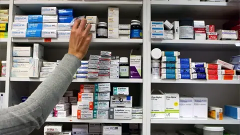 Julien Behal/PA Media A hand reaching for medication on a shelf