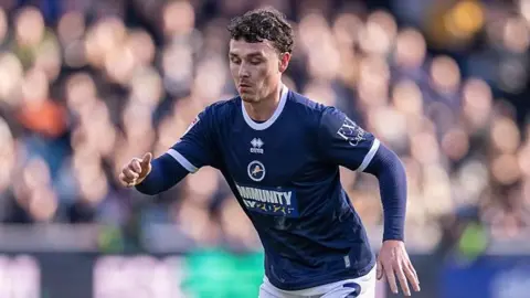 Dan McNamara in a dark blue Millwall shirt in action in a game against Blackburn in March