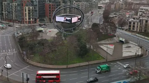 Wildstone Estates Ltd/Tate + Co Current advertising structure shows screen in orb on roundabout with cars, bus and lorry