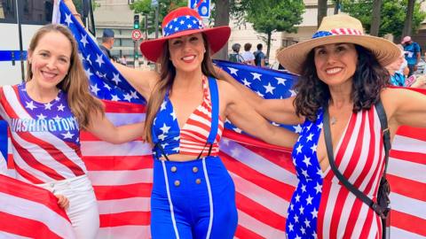 Marisa and two other women, adorned in US regalia, pose for a photo