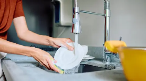 Getty Images Woman rinsing dishes