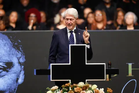 Getty Images Bill Clinton is on stage speaking in a suit, with one finger pointing up. 