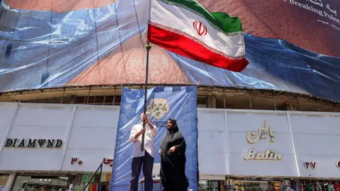 People hold up an Iranian flag in Tehran