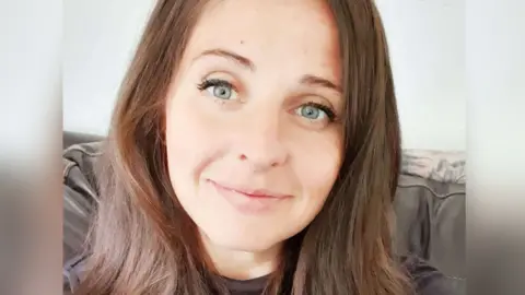 Laura-Jane Seaman smiling and looking directly at the camera, with long brown hair and blue eyes.
