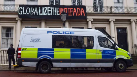Alamy A police van is parked outside the Diorama building in London with a police officer standing next to it, and above the van is a banner reading 'Globalize the intifada' hung on the building, in 2023.