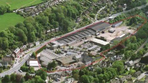An aerial shot of the site of the Brimscombe Port development in Stroud, which has a red ring drawn around it. It is in a valley with a main road to one side and is surrounded by trees and houses.