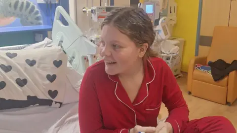 Family Photo A young girl in red pyjamas in a hospital bed. 