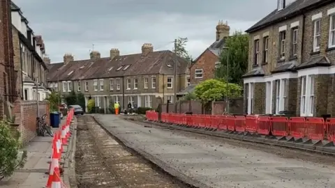 Barriers and cones lined up a road where a resurfacing work is being done.