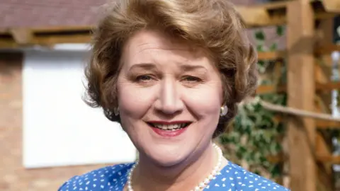 BBC Dame Patricia Routledge sorrindo como balde de Hyacinth para manter as aparências