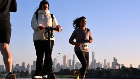 Getty Images Woman rides on an electric scooter near Albert Park Lake in Melbourne