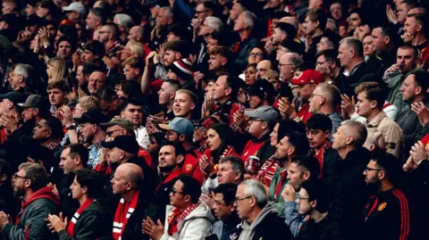 Manchester United fans applaud before kick off of a Premier League fixture against Liverpool