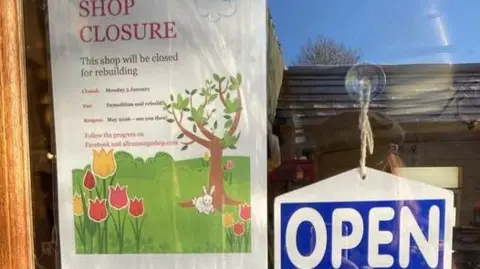 All Cannings Shop A sign on the shop door that explains when the shop will be closed for the rebuild. There is also a sign on the door that says "Open"