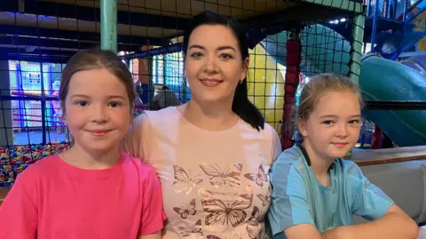 Paula McMahon sits with two children at an indoor play centre in Newcastle, County Down.