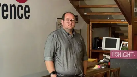 A man in a grey t-shirt and glasses