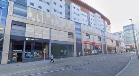 Google West Street in Gateshead. A row of retail units lines the road. One has a To Let sign in the window. it is surrounded by a vape shop and a Ladbrokes bookmakers.