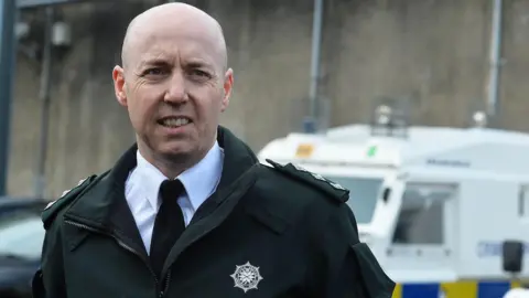 Pacemaker A file photo of Jon Burrows from 2017 in his Police Service of Northern Ireland uniform. The shell jacket is bottle green in colour and has the PSNI logo on its left breast. The shirt is white and tie is bottle green. Burrows is bald. Behind him the top of a white police Land Rover can be seen.