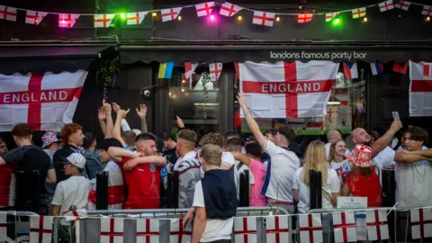 Fans in England kit take a break during half time of the UEFA Euro 2024 final match between England and Spain at a pub with England flags