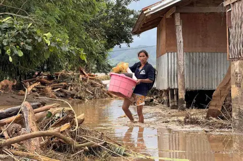 A resident carrying belongings evacuates from their flood-hit home in Tuao town,