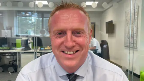 Ian Green is wearing a light shirt and dark tie