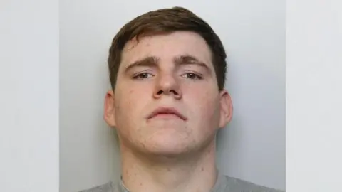 Custody image of James Doherty. He has brown hair and is wearing a grey top. He is looking directly into the camera.