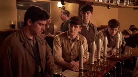 Gerontius Productions Limited A screengrab from The Choral, featuring four people standing in a wartime bar.