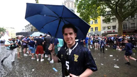 PA Media A Scotland fan holds an umbrella in Cologne during heavy rain