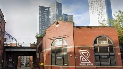 Rebellion a red brick building beneath Manchester's high rise buildigs 