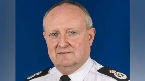 Cheshire's Chief Constable Mark Roberts is pictured in uniform. He has blue eyes and receding, short grey hair. 