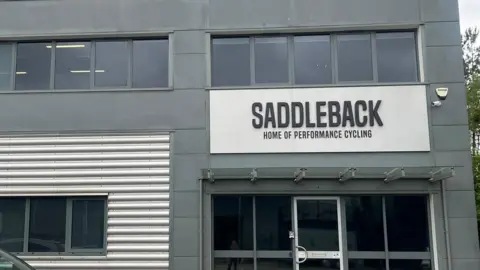 This picture was taken outside Saddleback's office/headquarters. The building uses two colours grey and silver. Underneath the company sign it reads, "home of performance cycling"