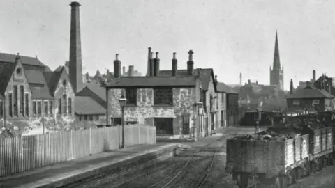 Leicester City Council A black and white image of the West Bridge station before it was demolished with St Mary De Castro's church spire behind