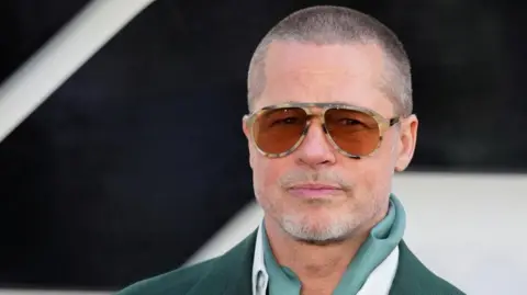 Reuters Actor Brad Pitt appears on the red carpet for his new movie F1. He is wearing a dark green suit with sunglasses