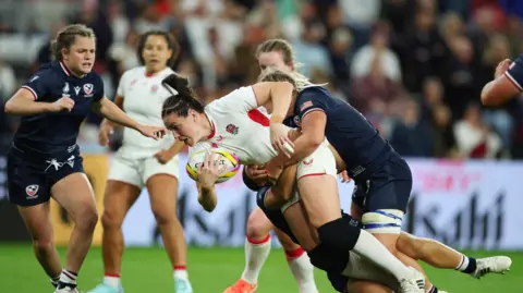 Reuters England's Emily Scarratt in action holding the ball and being tackled by Unites States players at the Stadium of Light.