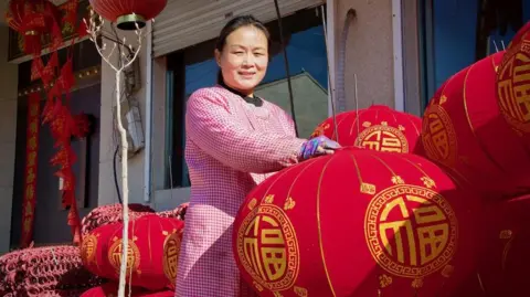 Chinese woman in pink surrounded by red Lunar New Year lanterns