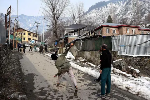 AFP via Getty Images TOPSHOT - This photograph taken on January 31, 2026 shows Kashmiri youth playing cricket along a street on the outskirts of Srinagar. The month-long 2026 ICC Mens T20 Cricket World Cup co-hosted by India and Sri Lanka begins on February 7. (Photo by Tauseef MUSTAFA / AFP via Getty Images)