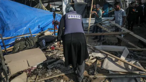 EPA A Palestinian journalist inspects damaged shelters following an Israeli airstrike inside the Al Aqsa Martyrs Hospital compound in Deir Al Balah, central Gaza Strip, 9 November 2024