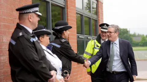 Joe Giddens/PA Wire Prime Minister Sir Keir Starmer with West Midlands Chief Constable Craig Guildford greets members of the West Midlands Police Force as he arrives at Arden Academy in Solihull