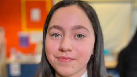 School pupil Ruby in her uniform sitting in class