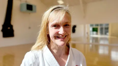 Paul Moseley/BBC Karate instructor Joanne Minnis, smiling in the dojo where she teaches