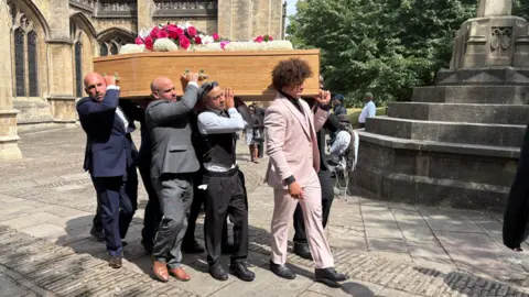 A group of men wearing suits containing the coffin which David 'Syd' Lawrence is in outside St Mary Redcliffe Church