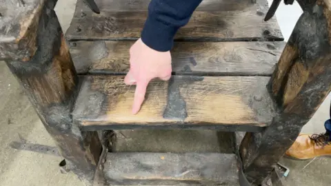 Richard Griza pointing to the wear on one of the seats