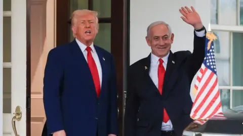 President Donald Trump speaks as Israeli Prime Minister Benjamin Netanyahu waves and smiles following a meeting in the White House, in Washington in April. 

Both men wear blue suits and red ties. 