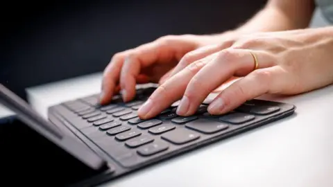Library picture of two hands typing on a laptop